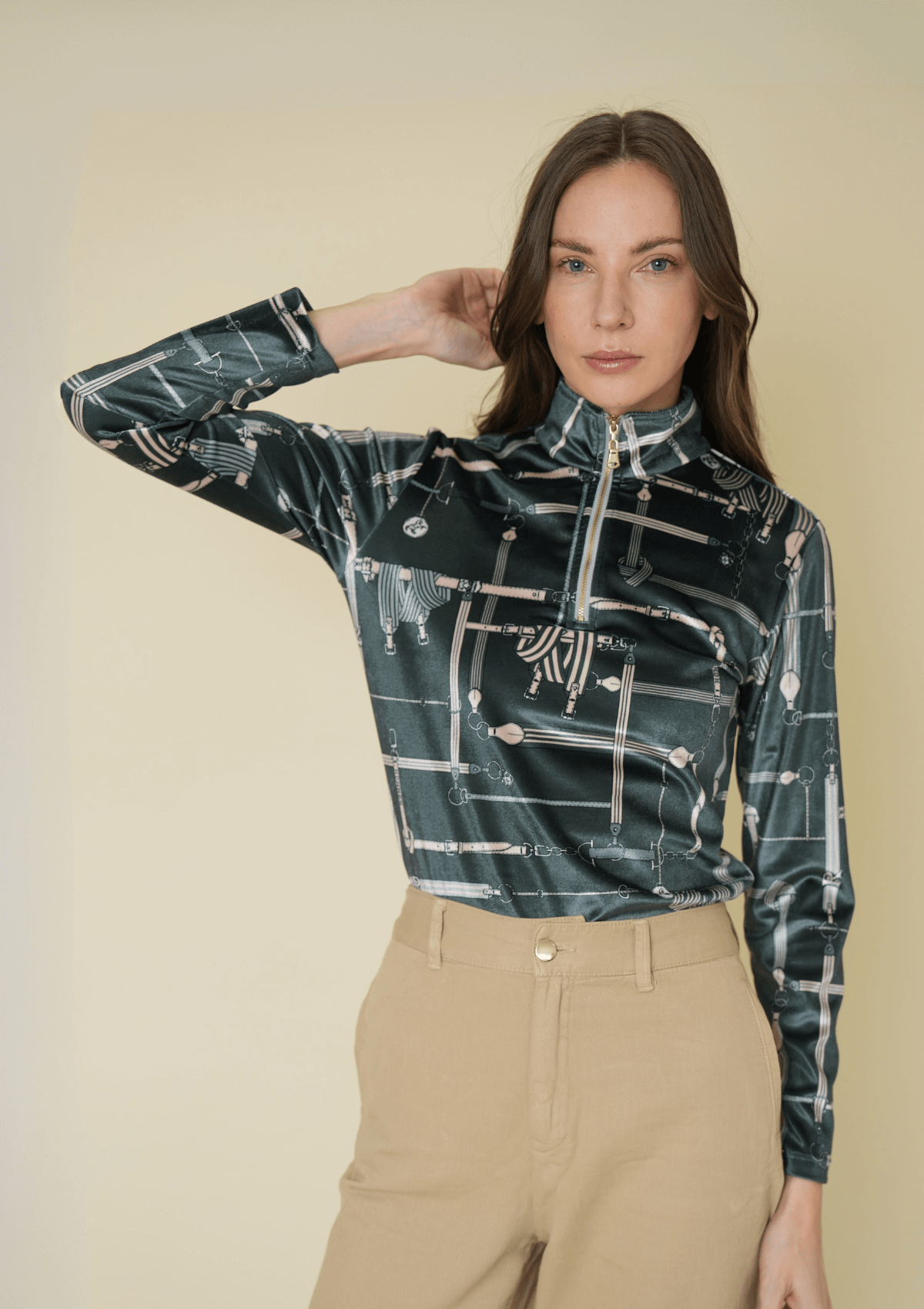 Woman wearing a patterned jacket and beige pants against a plain background